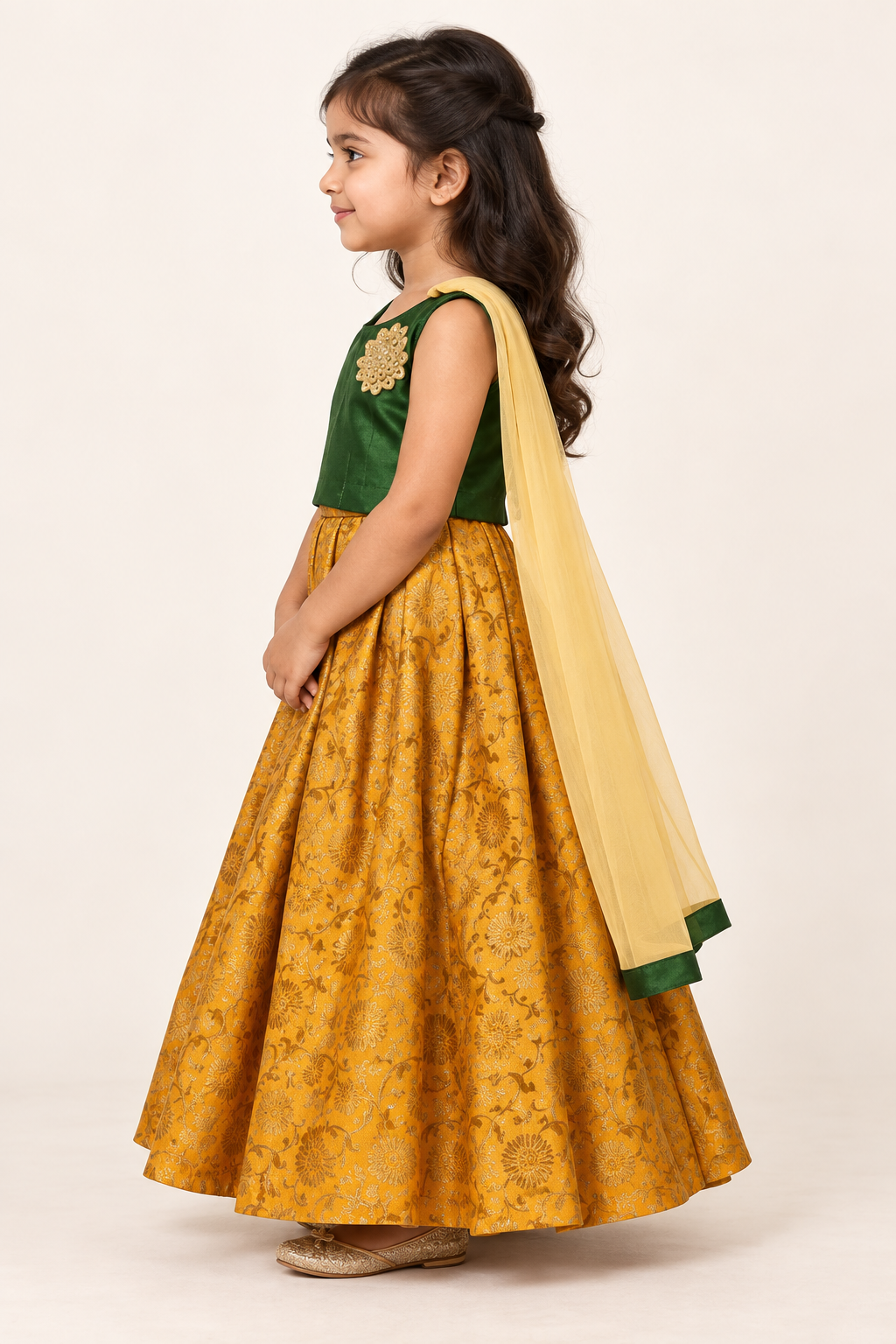 Side view of child wearing dark green choli and yellow brocade lehenga with net dupatta